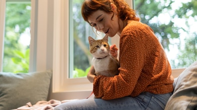 Woman in orange sweater holding a pet cat