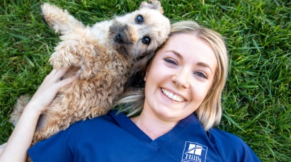 Hill's Pet profesionalac leži na travi s psom.